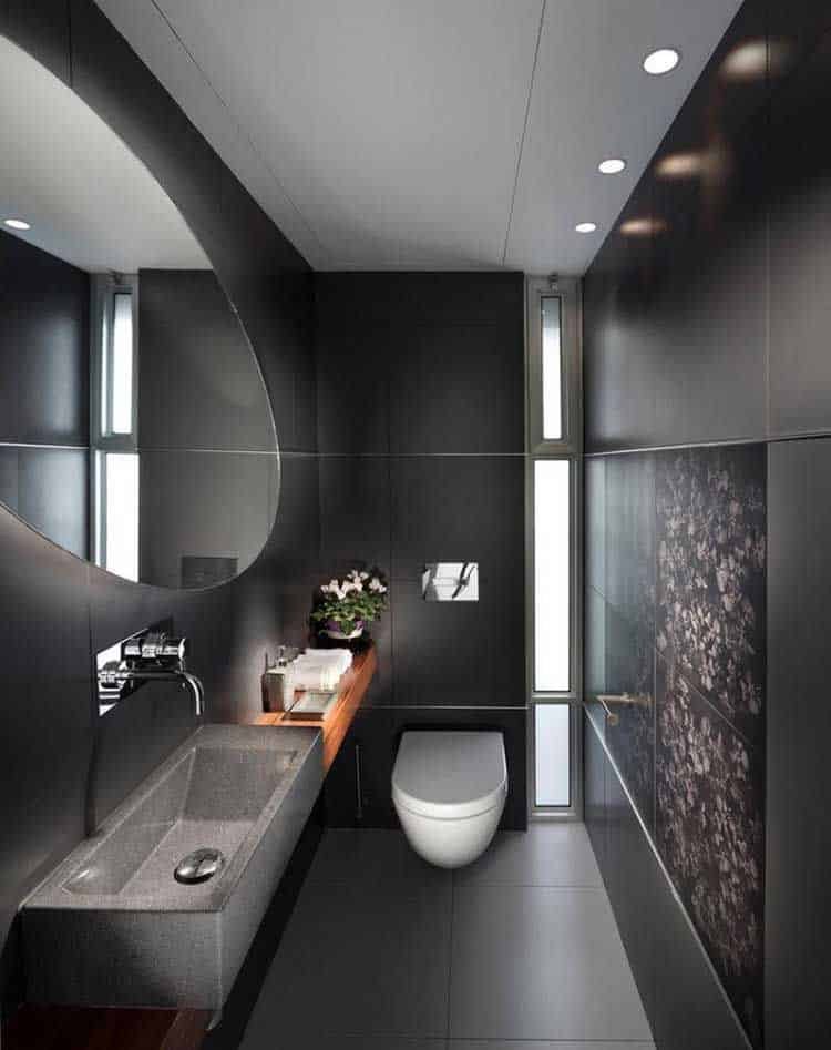 This black bathroom appears larger due to its lighting, usually a feature of light-toned rooms.