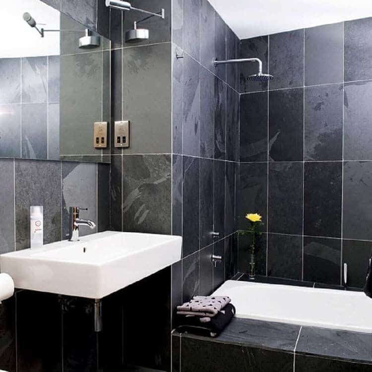 The wall with black and gray tiles gives this bathroom a unique, modern look.