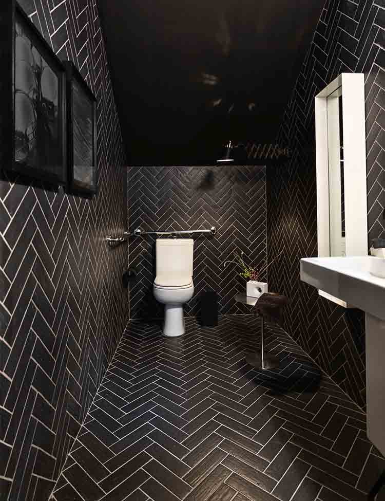 A modern bathroom with black walls and floors, featuring white lines creating unique shapes.
