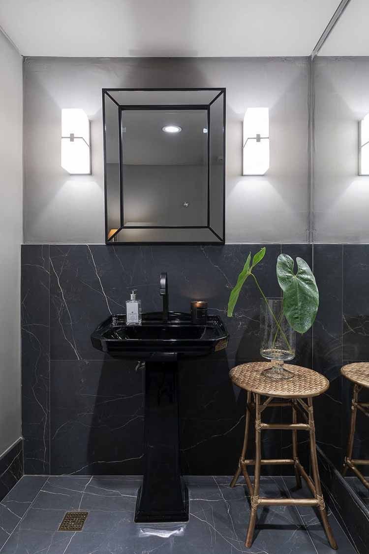 A black sink with black ceramic tiles create a modern, harmonious bathroom.