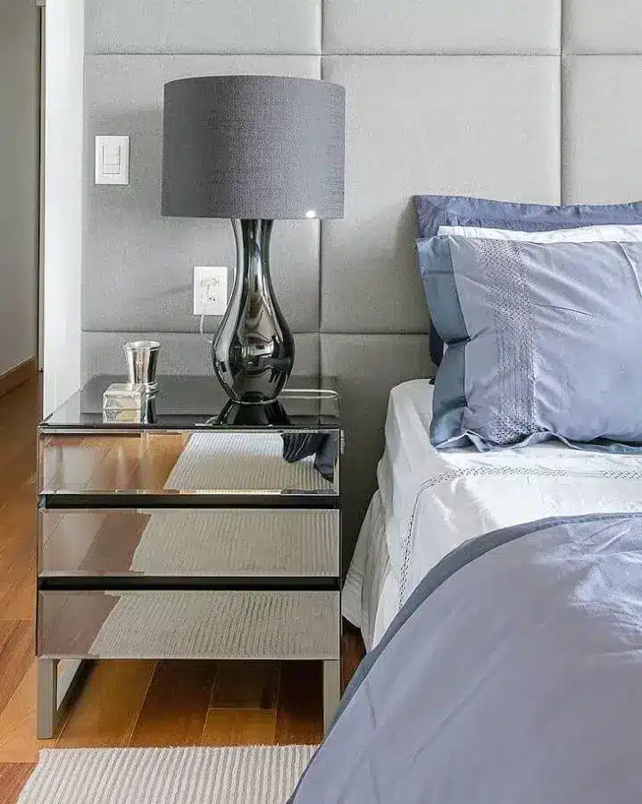 Decoração com criado mudo espelhado e abajur para quarto com base metálica.