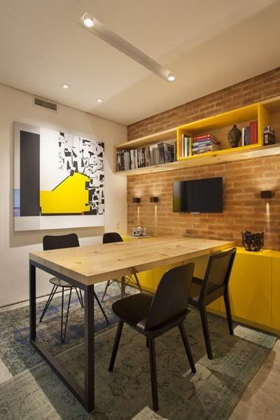 How about a little color and warmer lighting? The strong point of this design is the yellow color that makes up the countertop, shelf, and decorative elements. The rustic brick wall contrasts with the modern style of the small office.
