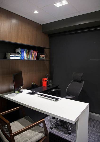 The white desk in the small office contrasts with the black wall, which faces the clients.