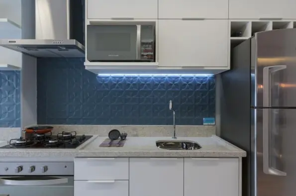 Ceramic for kitchen: blue wall cladding, white woodwork cabinets, black granite countertop with black cooktop and stainless steel hood – Project: Adriana Fontana