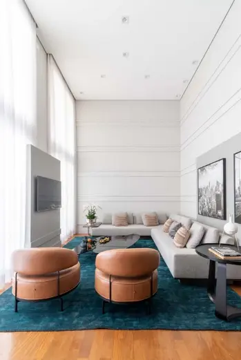 Gray tones contrast with the green rug and caramel armchairs – Project: Sabrina Salles | Photo: Julia Herman Photography