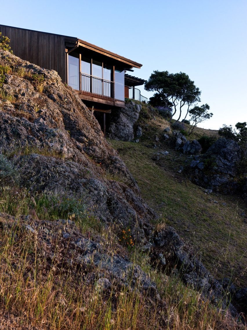 A casa construída em madeira vermelha, projetada pelo arquiteto Mickey Muennig, é elevada sobre um penhasco.