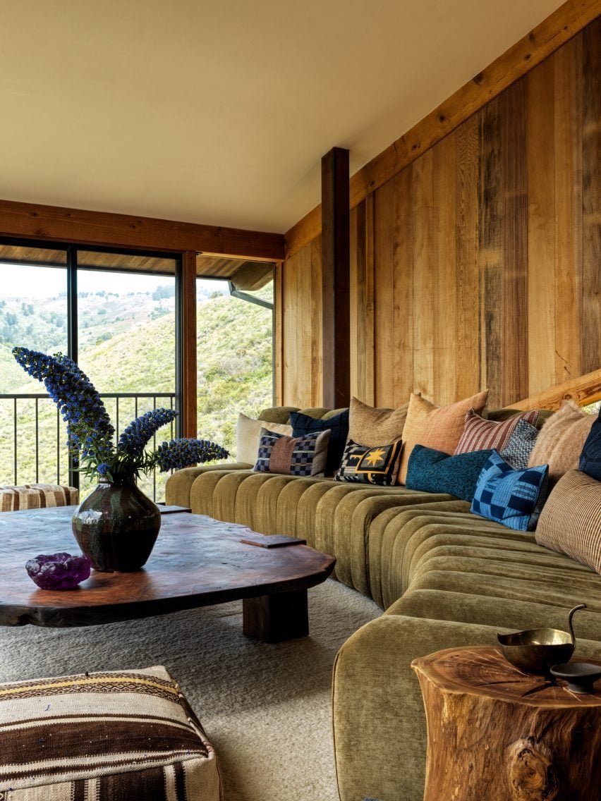 Sala de estar com painel de madeira vermelha e sofá curvado para proporcionar uma vista do canyon.