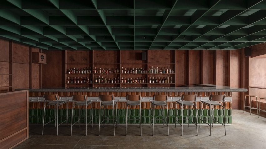 Bursa Bar em Kyiv, projectado por Nastia Mirzoyan, apresenta paredes de madeira compensada e um teto verde em formato de gradil, otimizando a acústica.