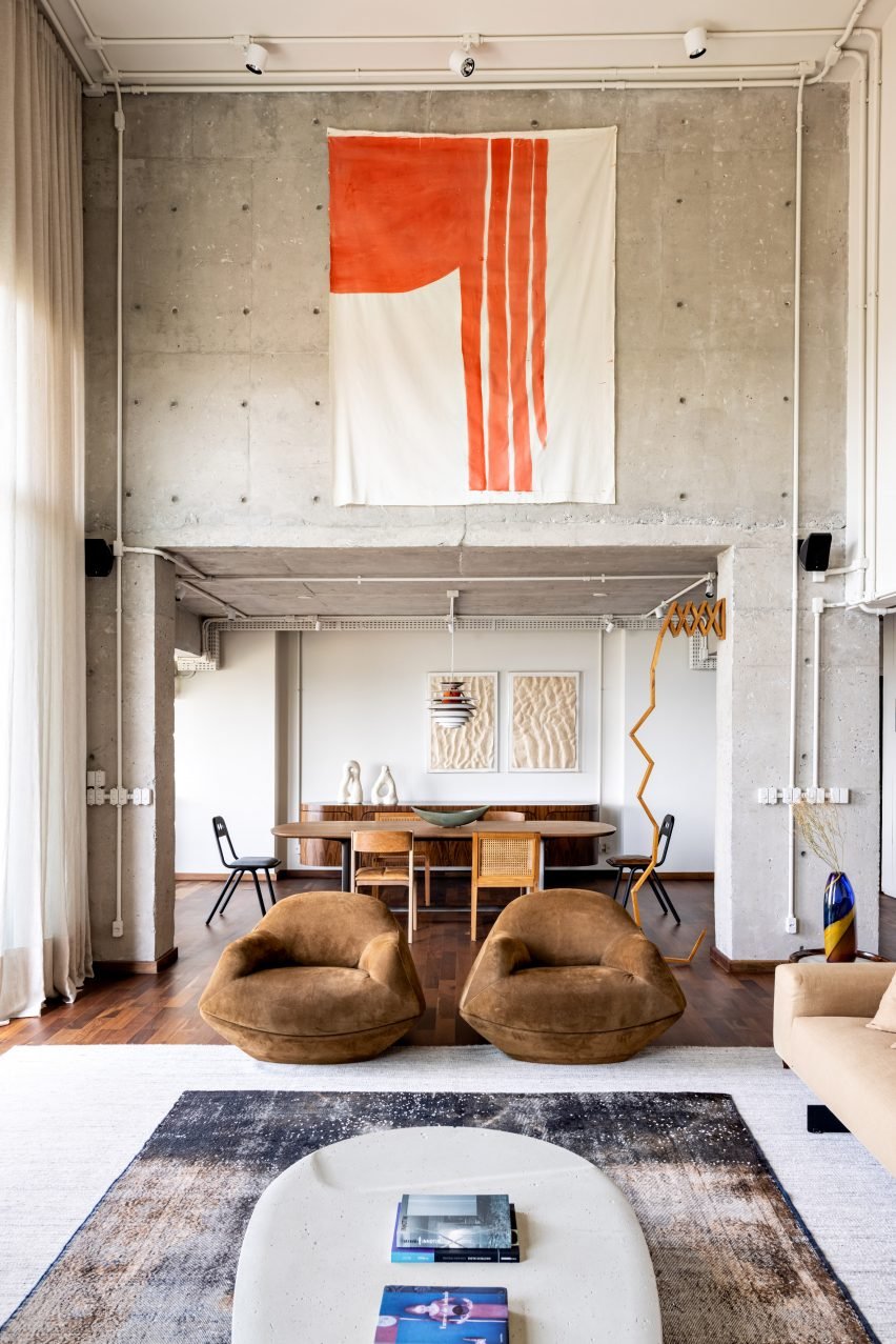 Gale Apartment living room featuring brown lounge chairs with concrete walls.
