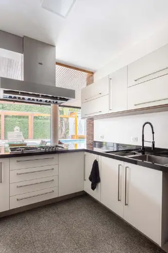 Cozinha branca com uma coifa de inox e um misturador black matte