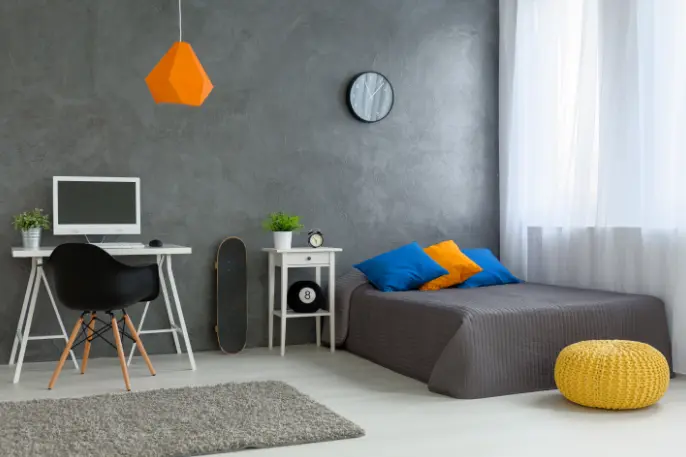 A simple masculine bedroom featuring a neutral base, burnt cement paint, and colorful details in the décor. Photo by Shutterstock.