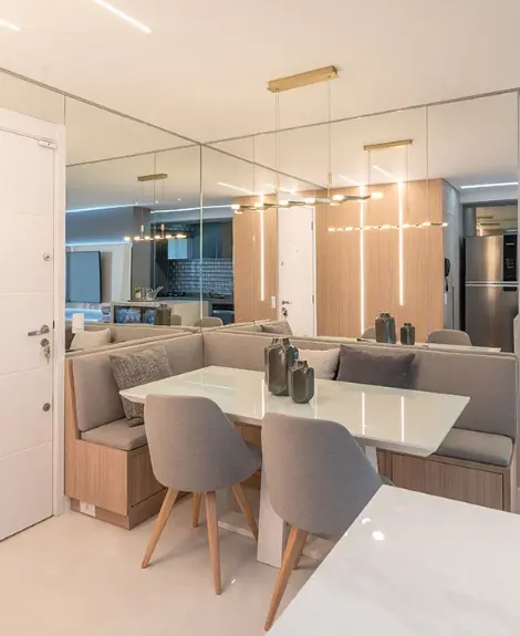 O espelho na sala posicionado atrás do sofá e da mesa de jantar faz o espaço parecer maior – Projeto: Fabiano Ravaglia | Foto: Denilson Machado, do MCA Estúdio/CASACOR