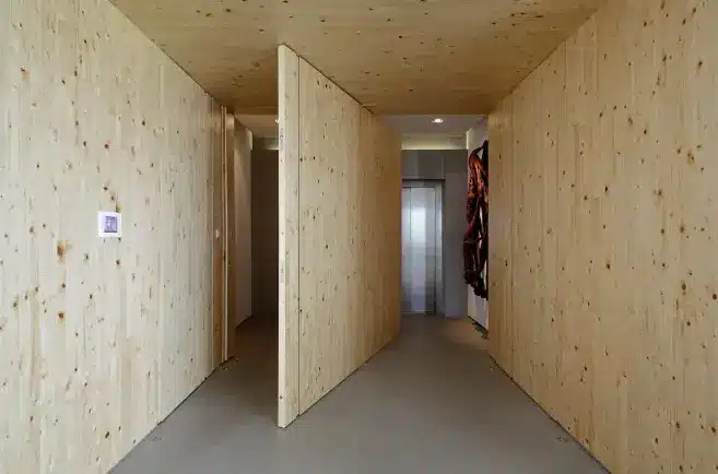 A porta de madeira pivotante é ampla, sem dobradiças visíveis e proporciona um visual limpo e elegante – Projeto: Consuelo Jorge