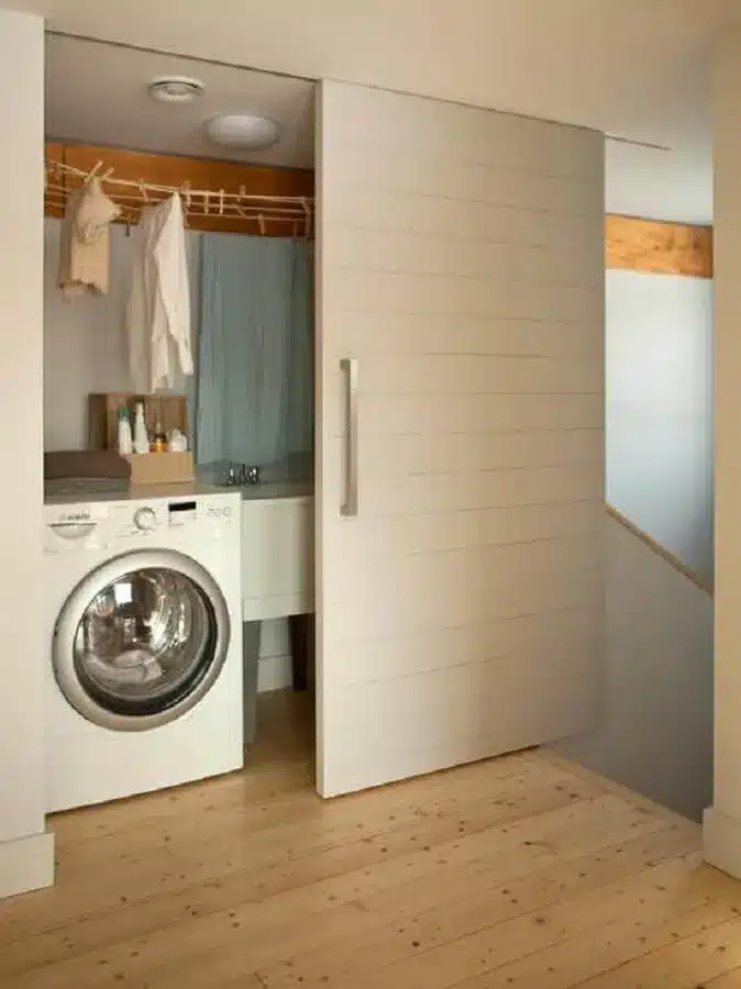 lavanderia pequena planejada com porta de correr e máquina de lavar e secar roupas – Foto Prosa de Designer