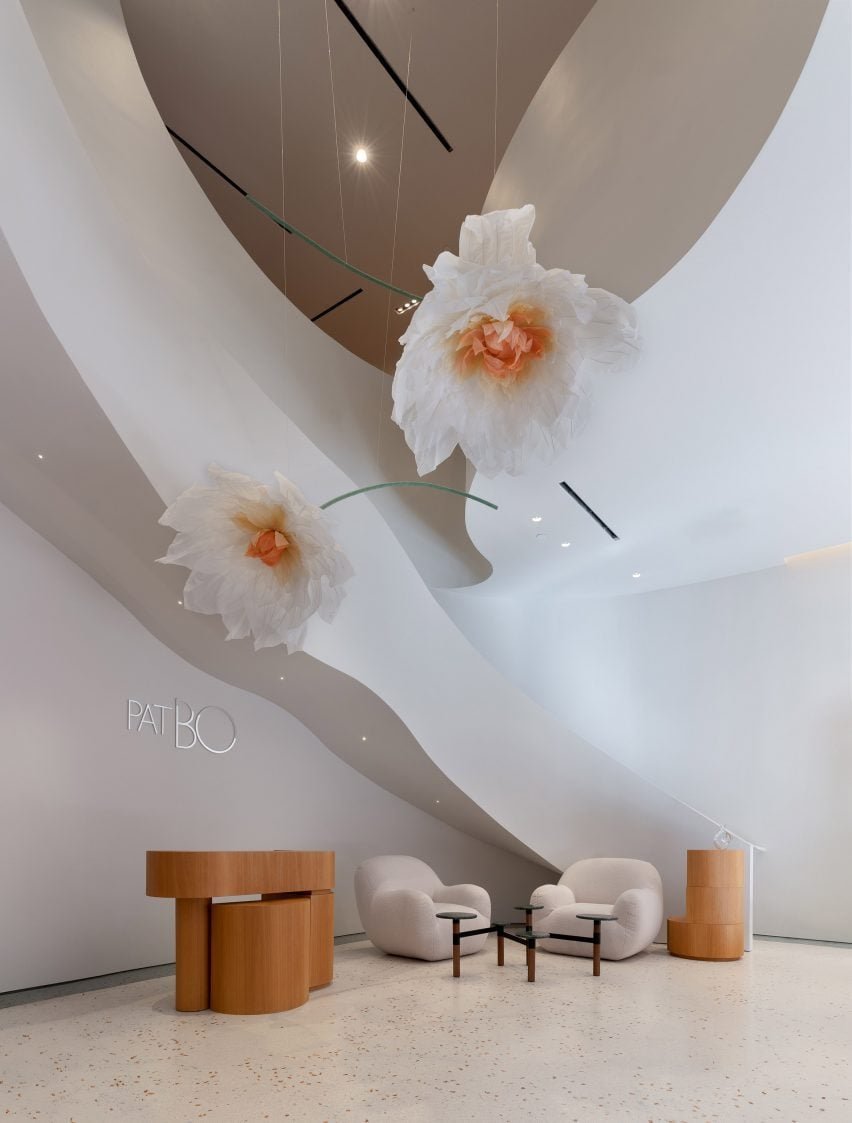 Um close da escada em espiral com um corrimão em forma de fita que circunda flores de seda oversized.