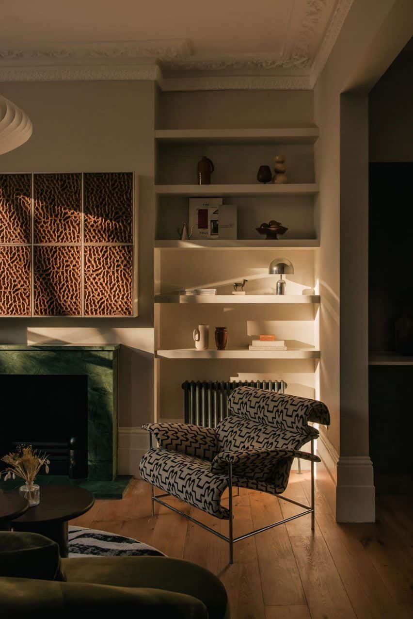 London townhouse living room with a graphic fabric chair and a marble green fireplace.