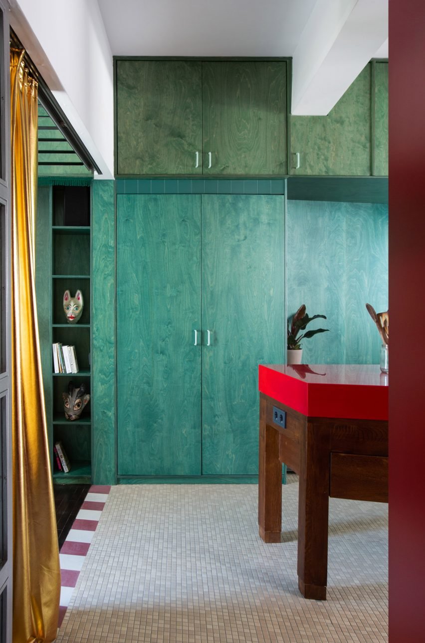 Stained plywood storage wall contrasting with kitchen cabinetry in a renovated apartment.