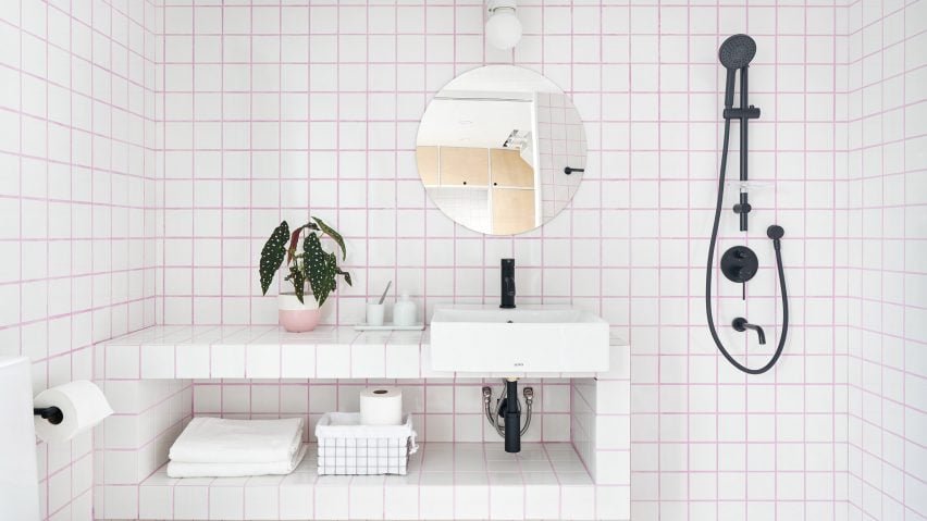 Banheiro com azulejos brancos e rejunte rosa.
